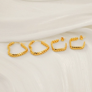 Golden wheat pattern heart earrings and square studs on white silk fabric background