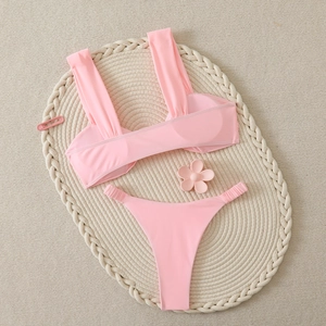 Détail d'un bikini rose deux pièces avec culotte froncée sur un tapis en rotin beige