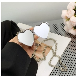 Detail shot of heart-shaped silver mirror pendant with chain for luxury shoulder bag