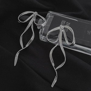 Elegant silver bow earrings with long flowing ribbon design on black fabric background
