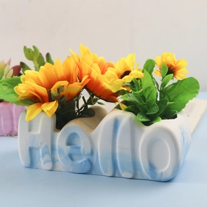 Detail of a blue and white marble pattern ceramic planter shaped as Hello with sunflowers