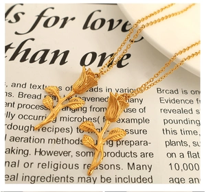 Detailed close-up of golden rose pendant texture and intricate leaf details on a fine chain