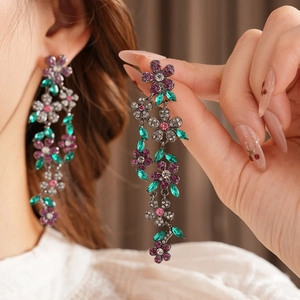 Gros plan de boucles d'oreilles vintage fleurs à pompons avec strass sur modèle