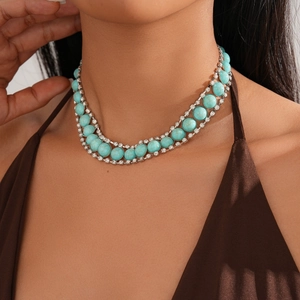 Detailed view of turquoise stones and rhinestones necklace on a model's outfit