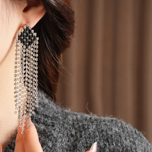 Close-up of luxury tassel earrings featuring silver rhinestones and black diamond-shaped gems