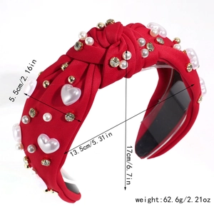 Detail of red knotted headband featuring white pearls, rhinestones, and heart charms