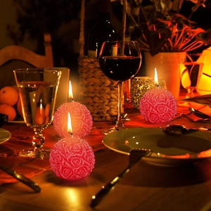 Detailed close-up of three red rose flower candles burning in a romantic dinner setting