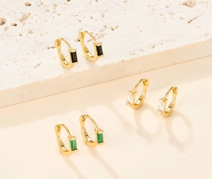 Detail view of gold S925 silver hoop earrings with emerald green and black zircons