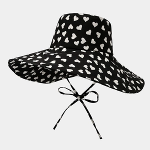 Detail of black sun hat with white heart pattern and adjustable windproof bow straps