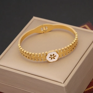 Macro detail of gold flower bangle with white enamel petals and central rhinestone