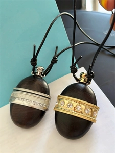 Detail of a dark wood bottle pendant necklace with gold and silver metal accents