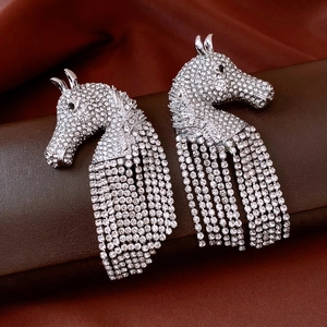 Close-up of silver horse head earrings featuring sparkling rhinestones and long tassels