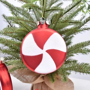 Christmas red and white spiral stripe round ornaments hanging on a green Xmas tree branch