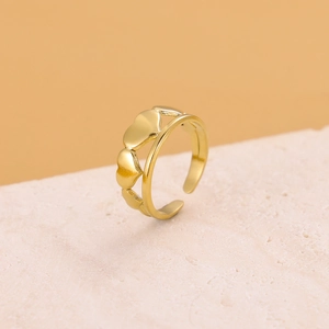 Close-up of golden adjustable heart-shaped ring on a textured stone surface