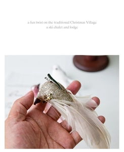 Detail of bird clip ornament with champagne feathers and glitter on a branch
