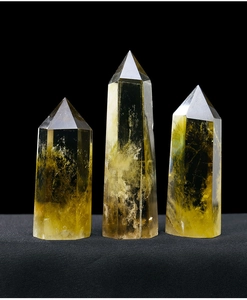 Close-up of three natural yellow citrine crystal hexagonal prisms on black velvet background