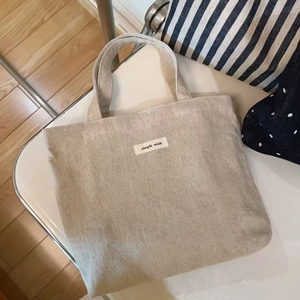 Minimalist beige canvas tote bag with simple wish label and dual handles in retro design