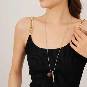 Detail of wooden acorn pendant and silver cylinder rod on a long sweater necklace