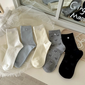 Détail de cinq paires de chaussettes en coton avec motifs nœuds et boutons décoratifs