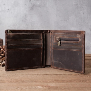 Vintage dark brown leather bifold wallet with card slots and coin pocket on a rustic desk