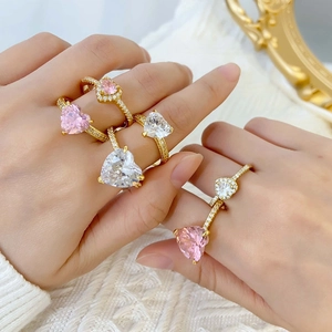 Close-up of hand wearing heart-shaped pink and white zircon engagement rings in gold