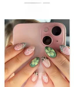 Detail of green floral and leopard print press-on nails with rhinestone accents