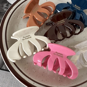 Detailed view of colorful oval pumpkin hair claws in various shades on a ceramic tray