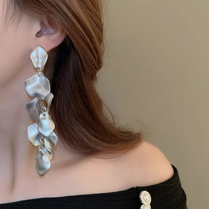 Detail of matte silver long layered petal fringe earrings worn by a model in profile