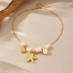 Gold starfish and shell pendant necklace with pink beads on beach sand background