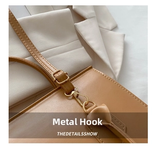 Detail of light brown leather bag strap with golden metal hook and precise stitching