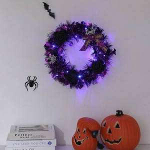 Detail of Halloween wreath with black roses, purple LED lights, and a festive bow on a wall
