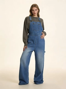 Détail de la salopette en jean bleu classique avec jambes larges et boucles en métal