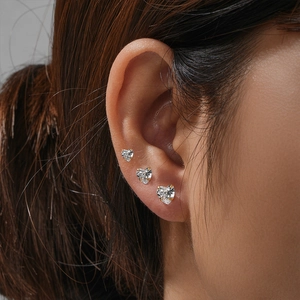 Detailed view of three-piece silver heart stud earrings with clear zircon on ear