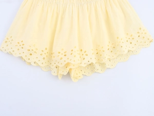 Detail of light yellow poplin shorts with floral embroidery and scalloped hemline