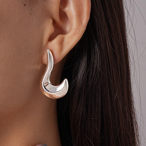 Close-up of minimalist irregular silver curved stud earrings worn by a model
