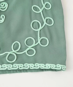 Close-up of intricate 3D floral embroidery and fretwork pattern on teal chiffon fabric