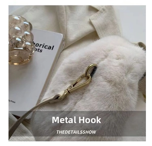 Detail of light gold hardware hook and fluffy faux fur texture on a white plush handbag