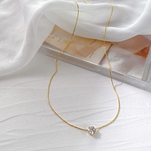 Elegant gold 6-prong solitaire diamond pendant necklace on a clean white textured surface