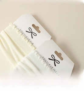 Dettaglio dei polsini delle calze a coste color crema con alta elasticità e trama premium