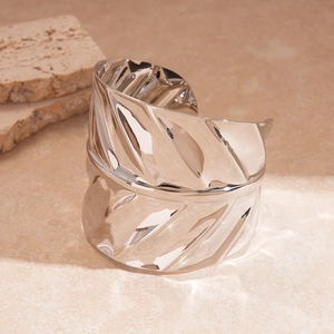 Detailed view of wide silver metal cuff bracelet featuring textured leaf vein pattern