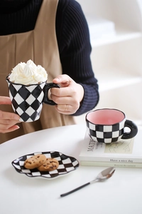 Close-up of checkered ceramic mug and saucer set featuring a warm latte on a cozy table