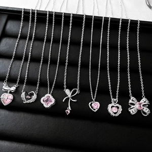Close-up of assorted silver necklaces with pink zircon hearts and bow pendants