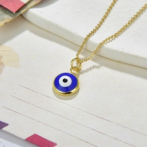 Close-up of golden evil eye pendant with blue enamel on textured stone background