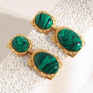 Gros plan de boucles d'oreilles en acier doré avec pendentifs en malachite verte