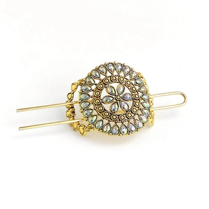 Detail of vintage gold hairpin featuring rainbow rhinestones and elegant hollow floral pattern