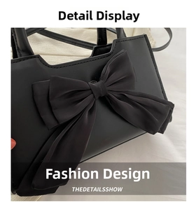 Detail shot of black faux leather handbag featuring a large decorative satin bow design