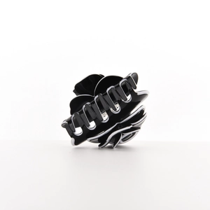 Detail of black camellia hair claw clip with white borders and strong spring mechanism