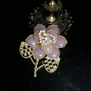 Elegante Vintage-Blumenbrosche in Rosa mit Kristallen und Goldrahmen auf Reflexionsfläche