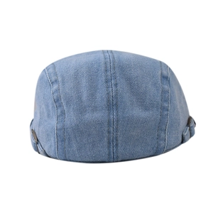 Macro view of light blue denim beret showing twill texture and metal side adjustment buckles