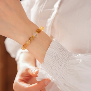 Detail of beaded bracelet with amber crystals and gold accents on a female wrist